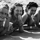 Black & white vintage photo of people in swimsuits on the beach eating ice cream cones